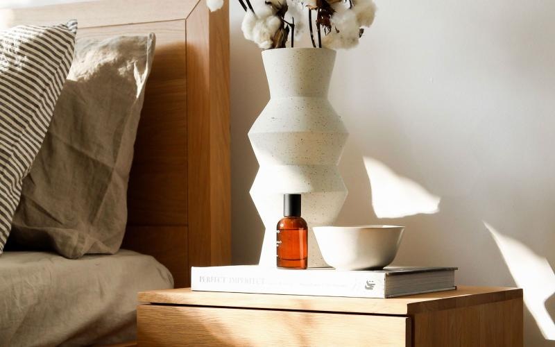 a vase with cotton stems on a bedside table